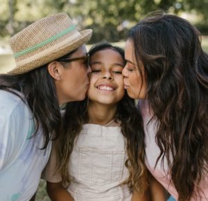 Parents Kissing Their Daughter