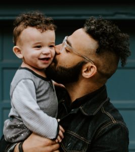 man carrying baby boy and kissing on cheek