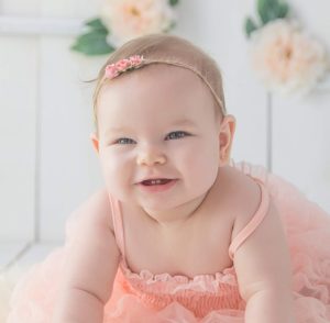 girl crawling on white floor while smiling